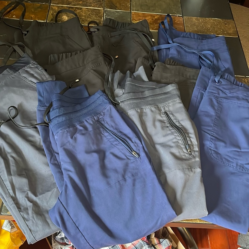 9 pair of scrub pants 2 are joggers. Colors are grey navy and black